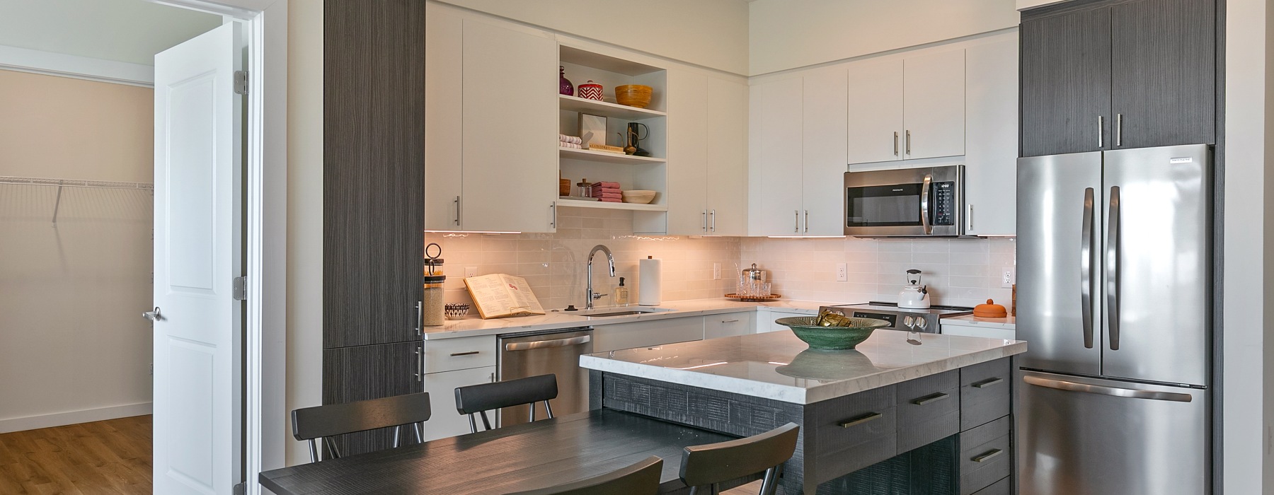 a kitchen with a large island with a table and a sink a fridge and stovetop