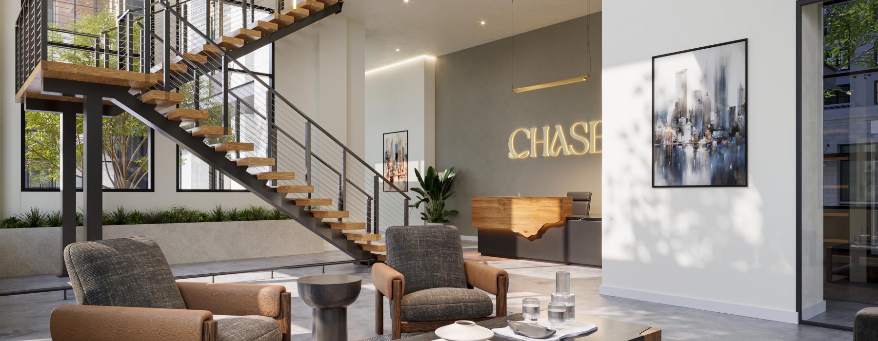 a lobby with a staircase and chairs with a table and many windows